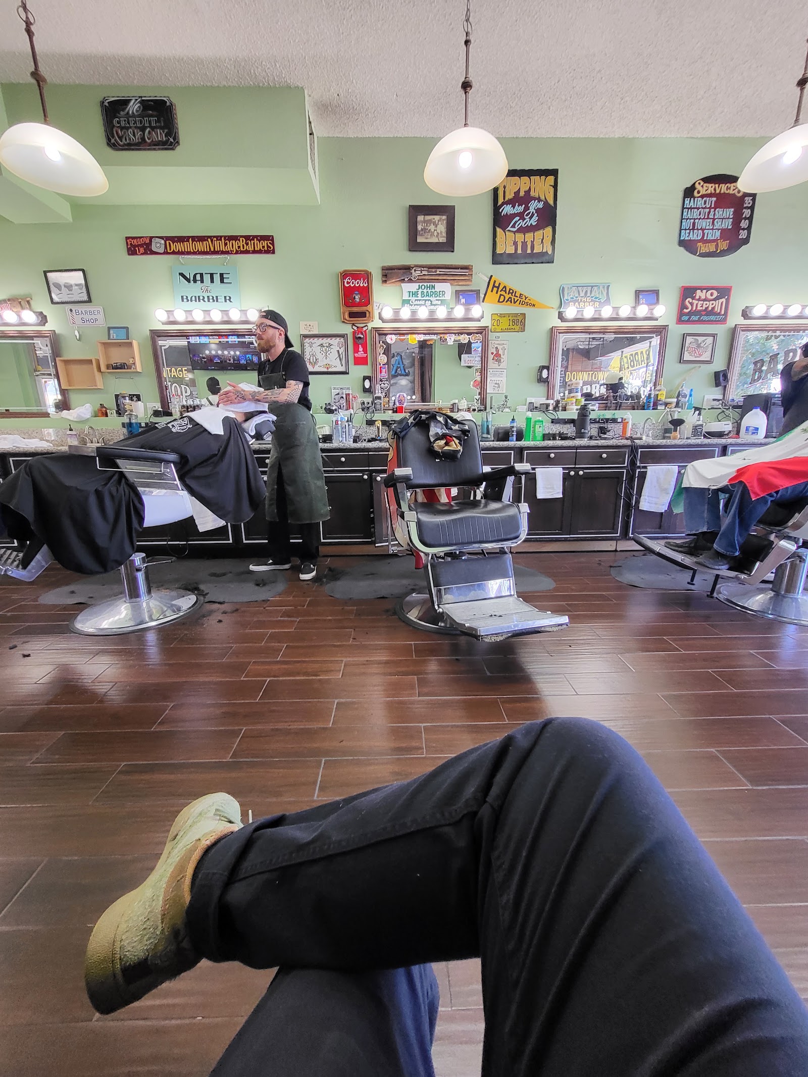 Wide barbershop interior with multiple chairs, barbers working and vintage signage